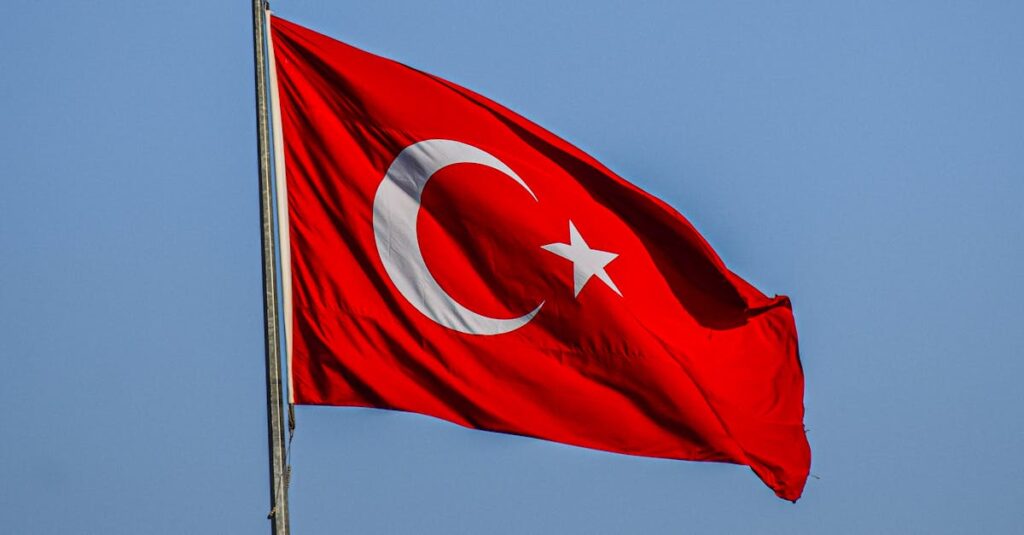 Beautiful Turkish flag featuring crescent and star on a clear blue sky background.