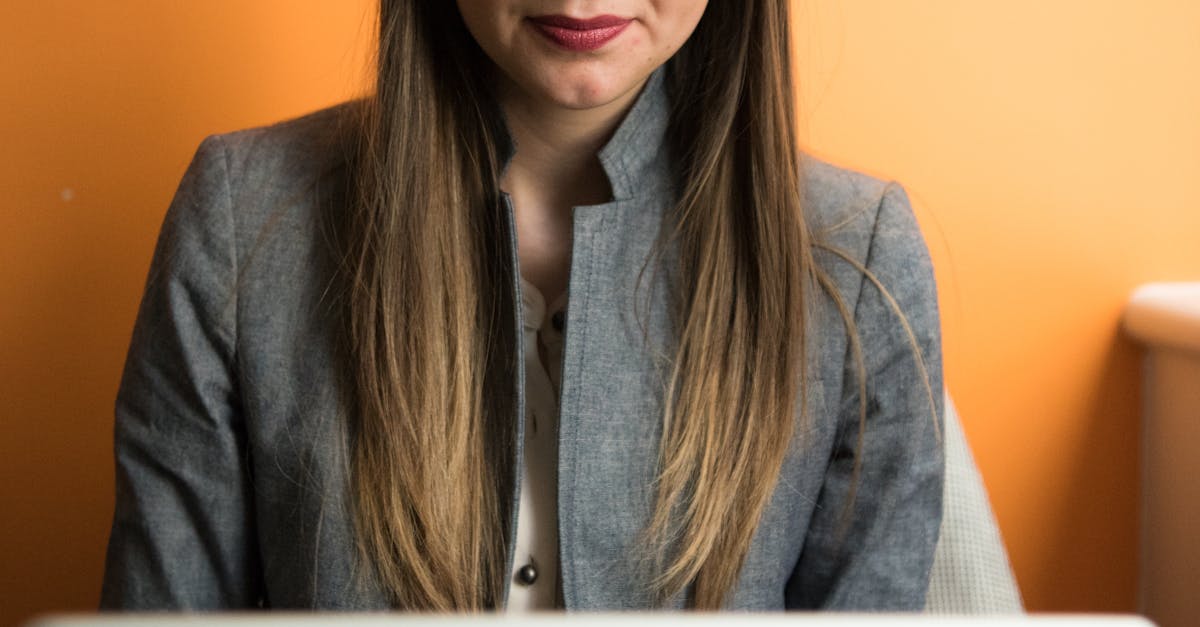 Focused businesswoman using a laptop indoors with an orange background.