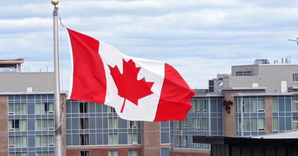 Canadian flag on a pole waving against modern buildings in Halifax, Nova Scotia.