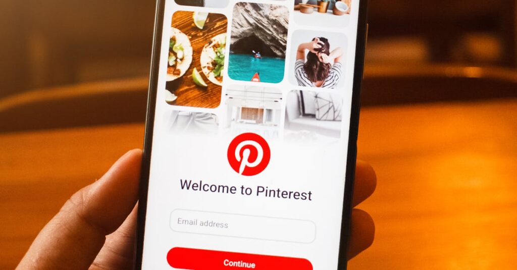 Close-up of a hand holding a smartphone displaying the Pinterest login screen indoors.