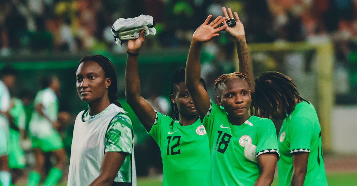 Nigerian female football players celebrating after a match in their green kits.