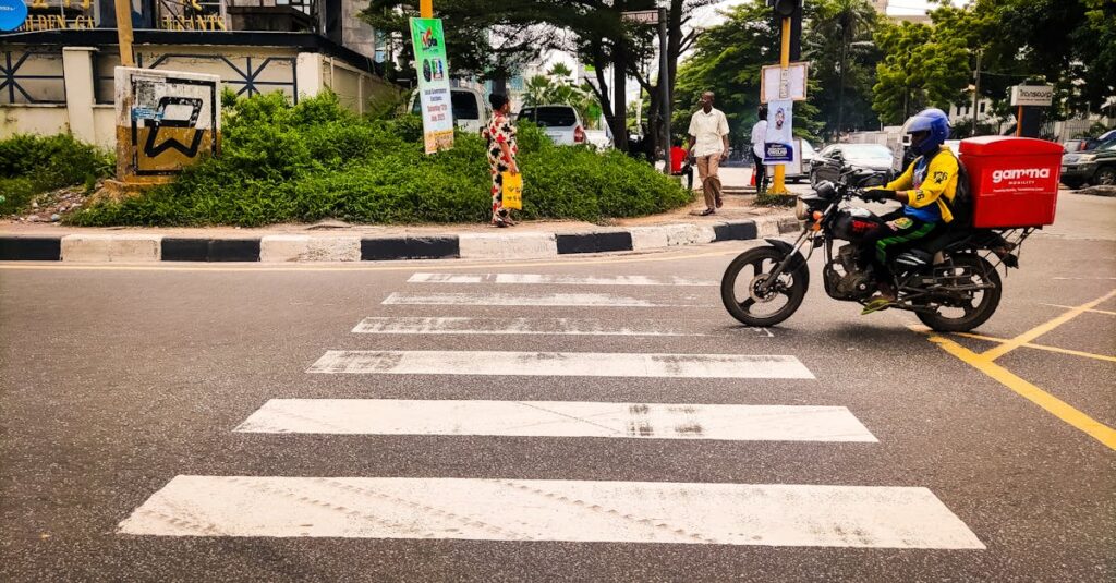 Dynamic street view featuring a delivery motorbike and pedestrians in Lagos, Nigeria.