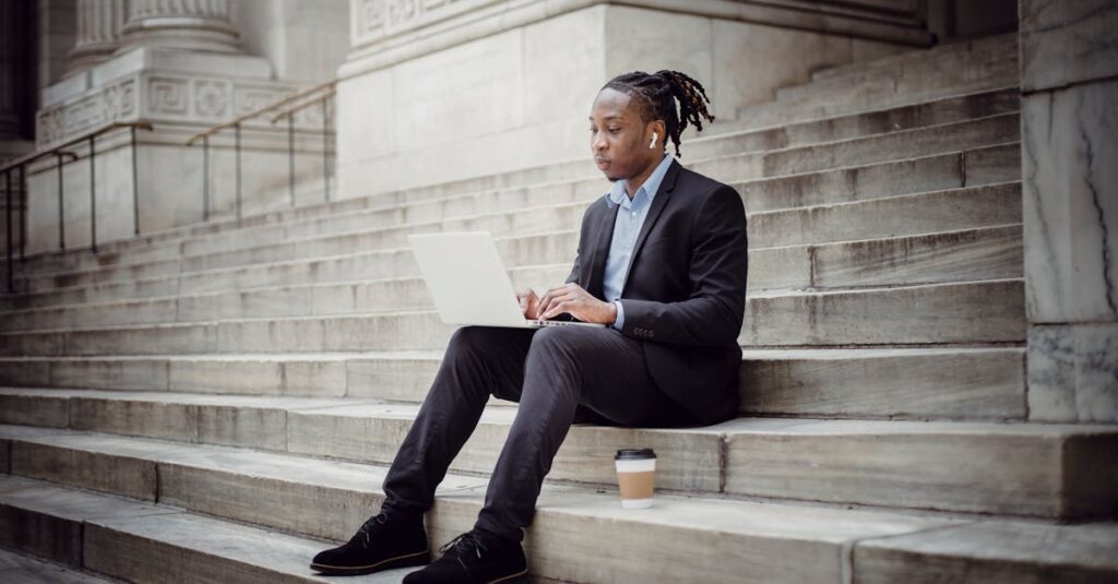 Confident businessman using laptop on urban steps, focused on work.