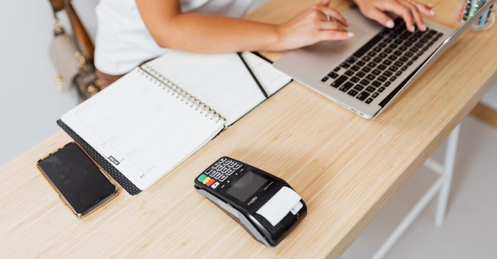 Modern workspace featuring a laptop and payment terminal setup on a wooden table.