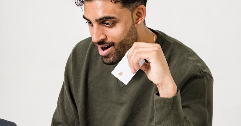 Excited man uses a laptop and credit card for online shopping indoors.