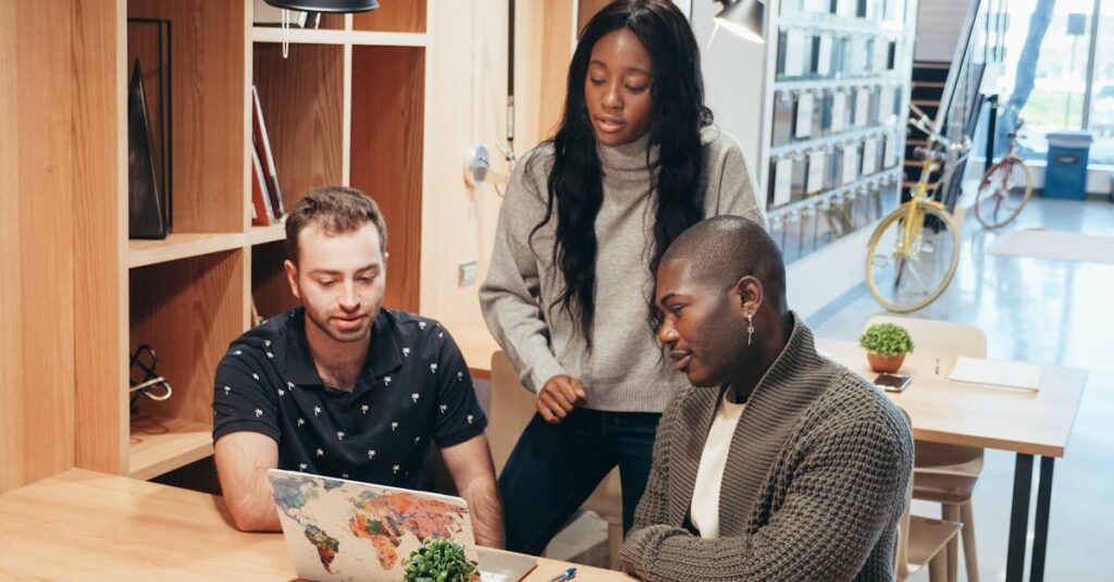 A diverse team discussing ideas around a laptop in a contemporary office setting.