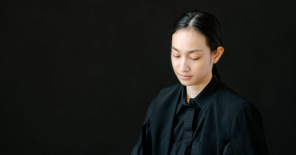 Focused businesswoman using a laptop against a black background, embodying professionalism and elegance.