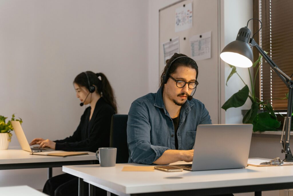 Two call center employees working diligently with headsets in the office.