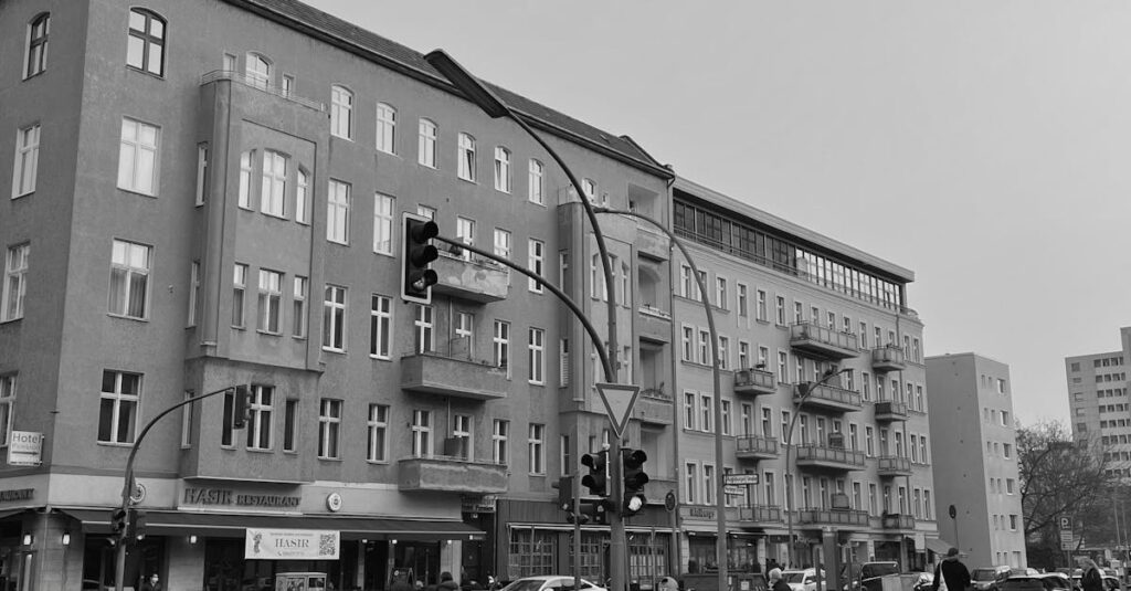 Black-and-white view of a busy street in Berlin with pedestrians and vehicles.