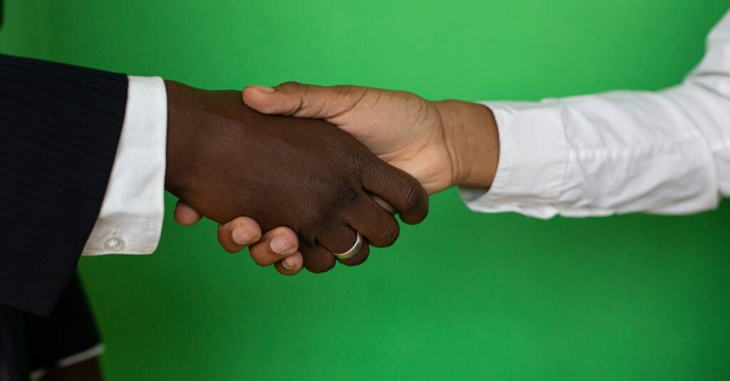 Two diverse hands shaking towards a successful business deal on a green background.
