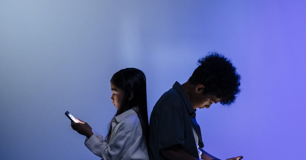 Children sitting back to back using smartphones, illuminated by screen light in a dark, minimal studio setting.