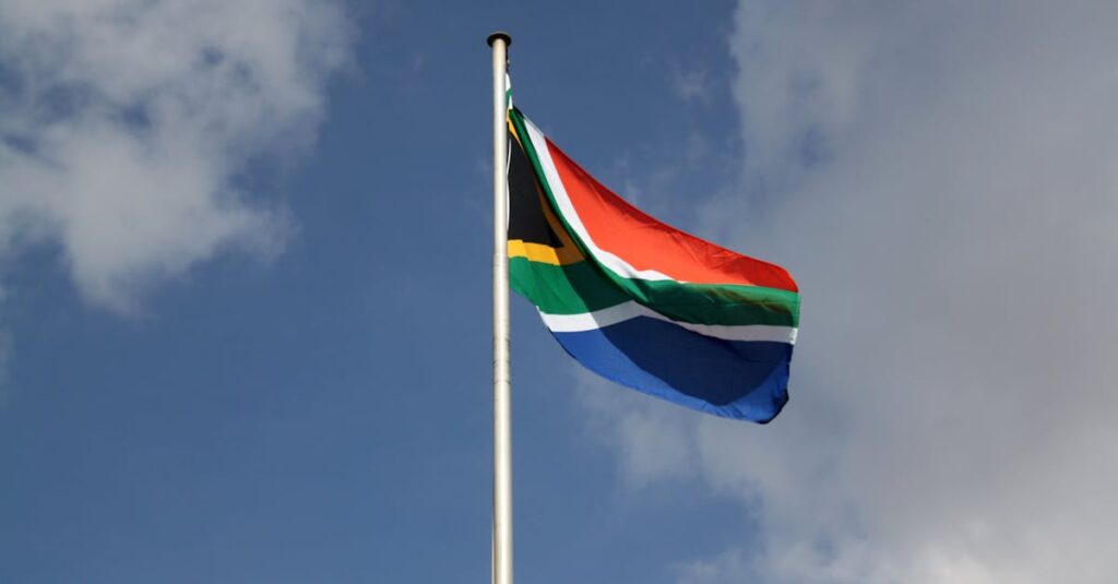 Vibrant South African flag waving proudly against a blue sky with clouds.