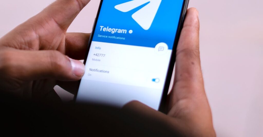 Close-up of hands holding a smartphone with the Telegram app open on the screen.