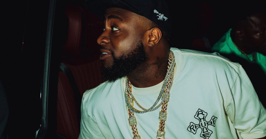 Man with hat and chain exiting a car at night, casual urban style.