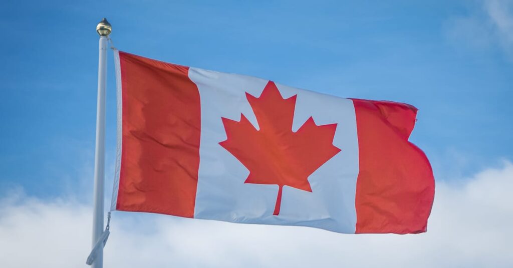 A vibrant Canadian flag waving in the breeze against a bright blue sky, symbolizing national pride.