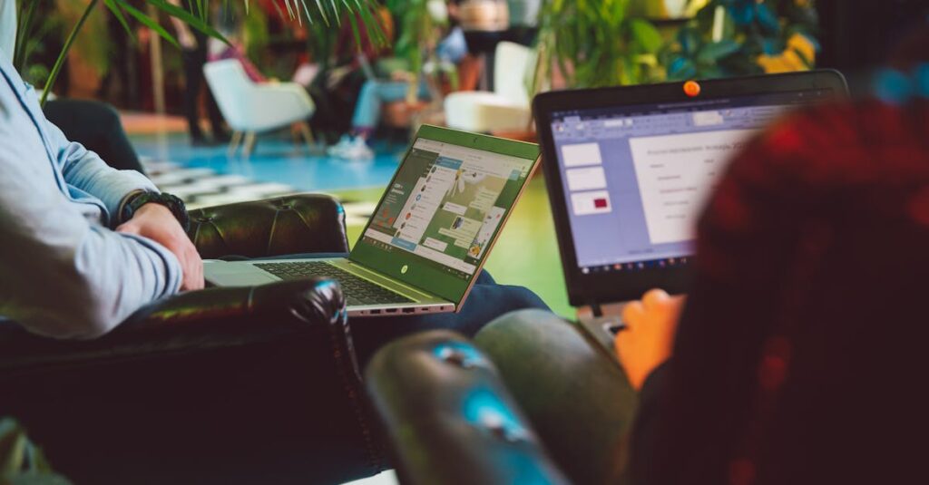 Two individuals working on laptops in a cozy indoor setting surrounded by plants.