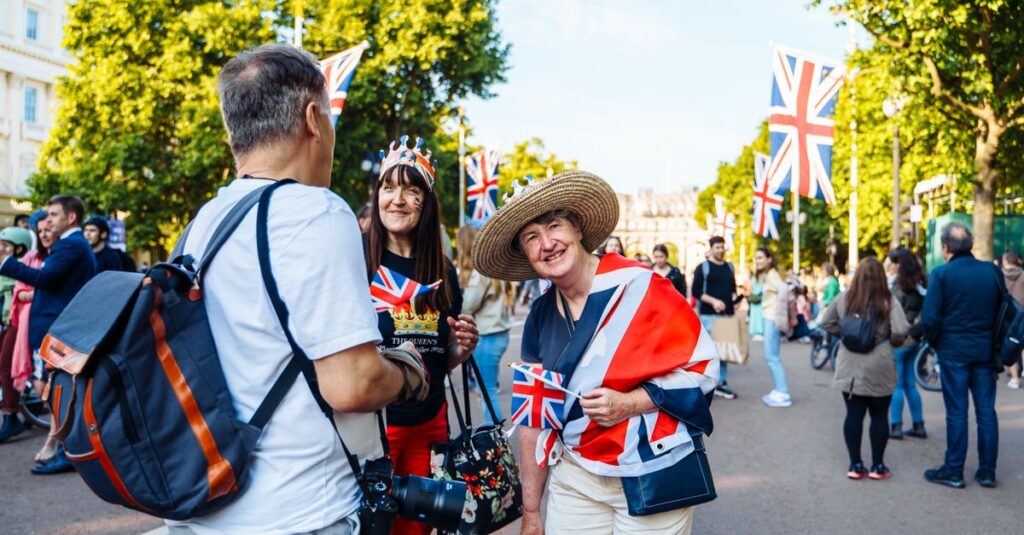 Joyful street scene in Central London with people celebrating under Union Jack flags, capturing vibrant city life.