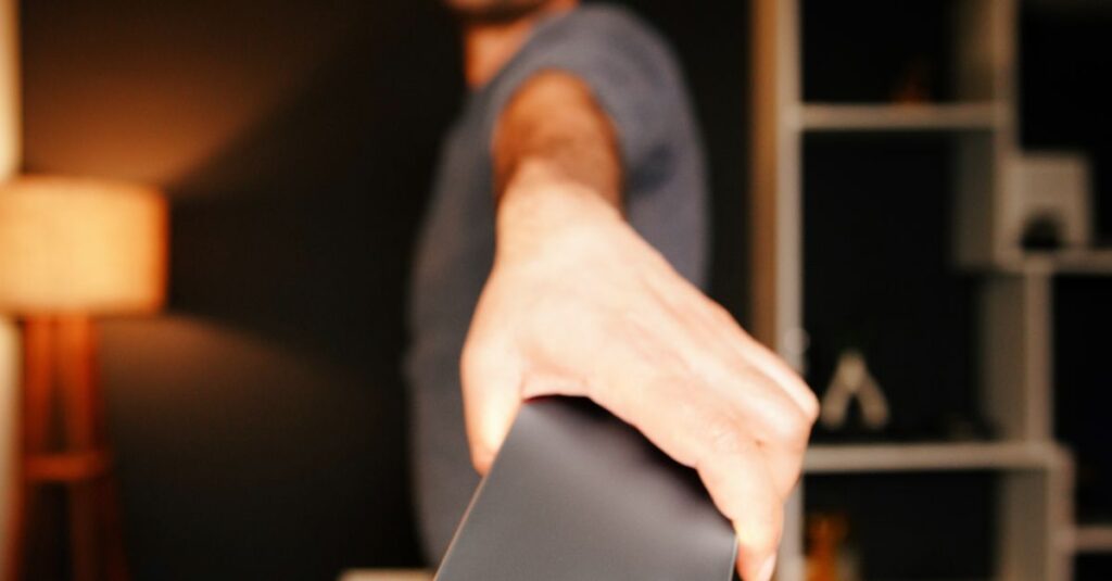 A man holds a smartphone towards the camera in a stylish indoor setting, showcasing device features.