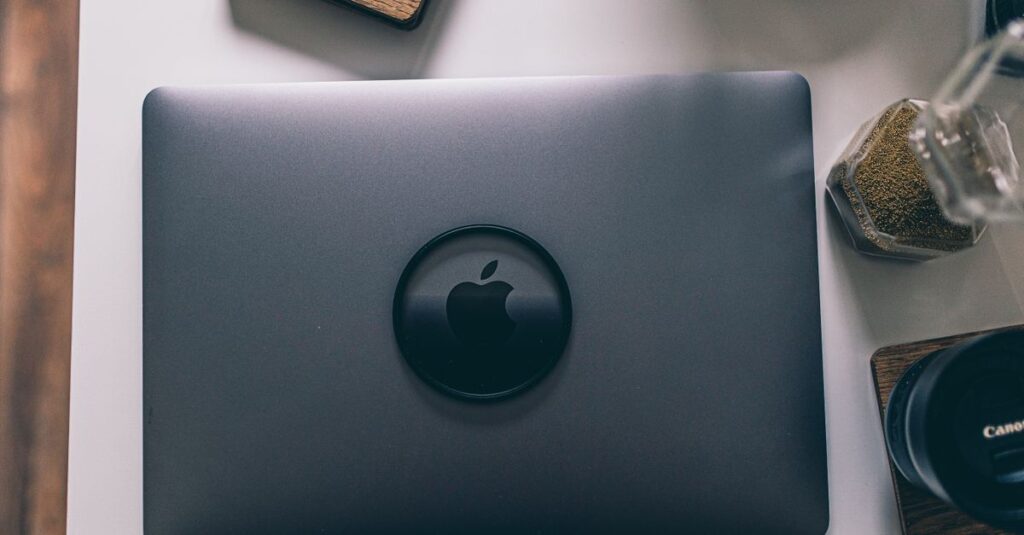 A sleek laptop is surrounded by camera lenses and stylish desk items in a modern flatlay setup.
